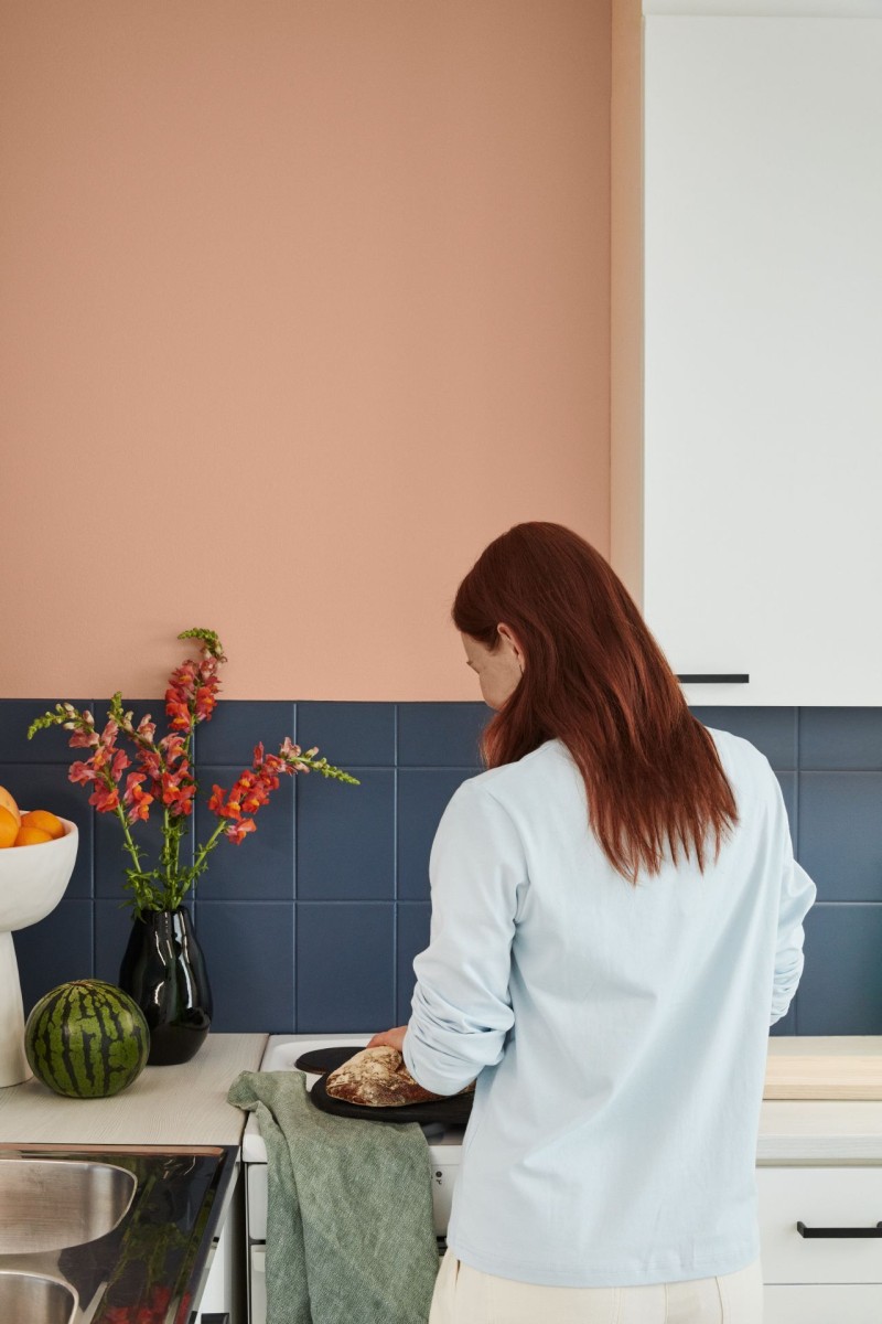 woman in front of warm peach kitchen wall and blue painted tile backsplash