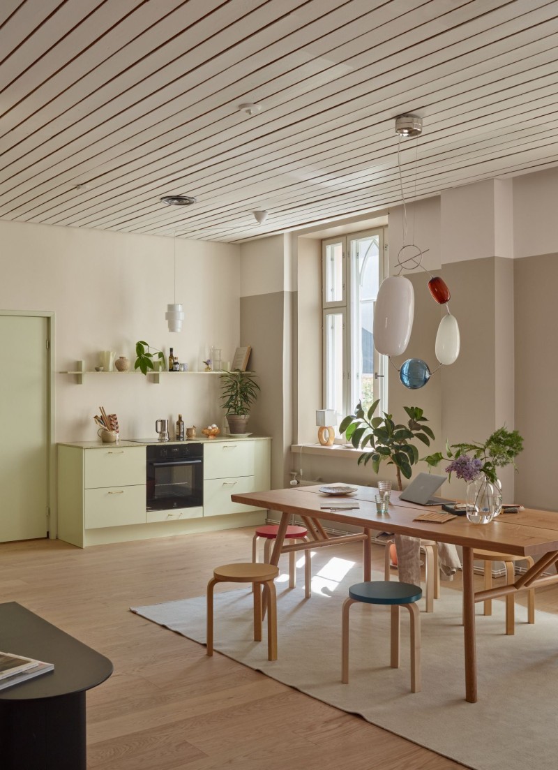 studio meeting space with beige colour wall and light green color in kitchen cabinet