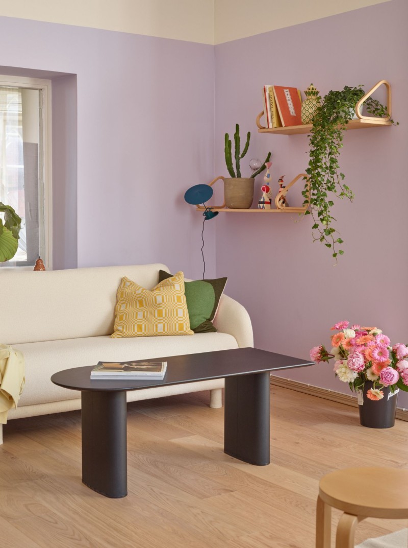lounge area with light lilac colour section on walls and beige sofa and other wooden furniture element