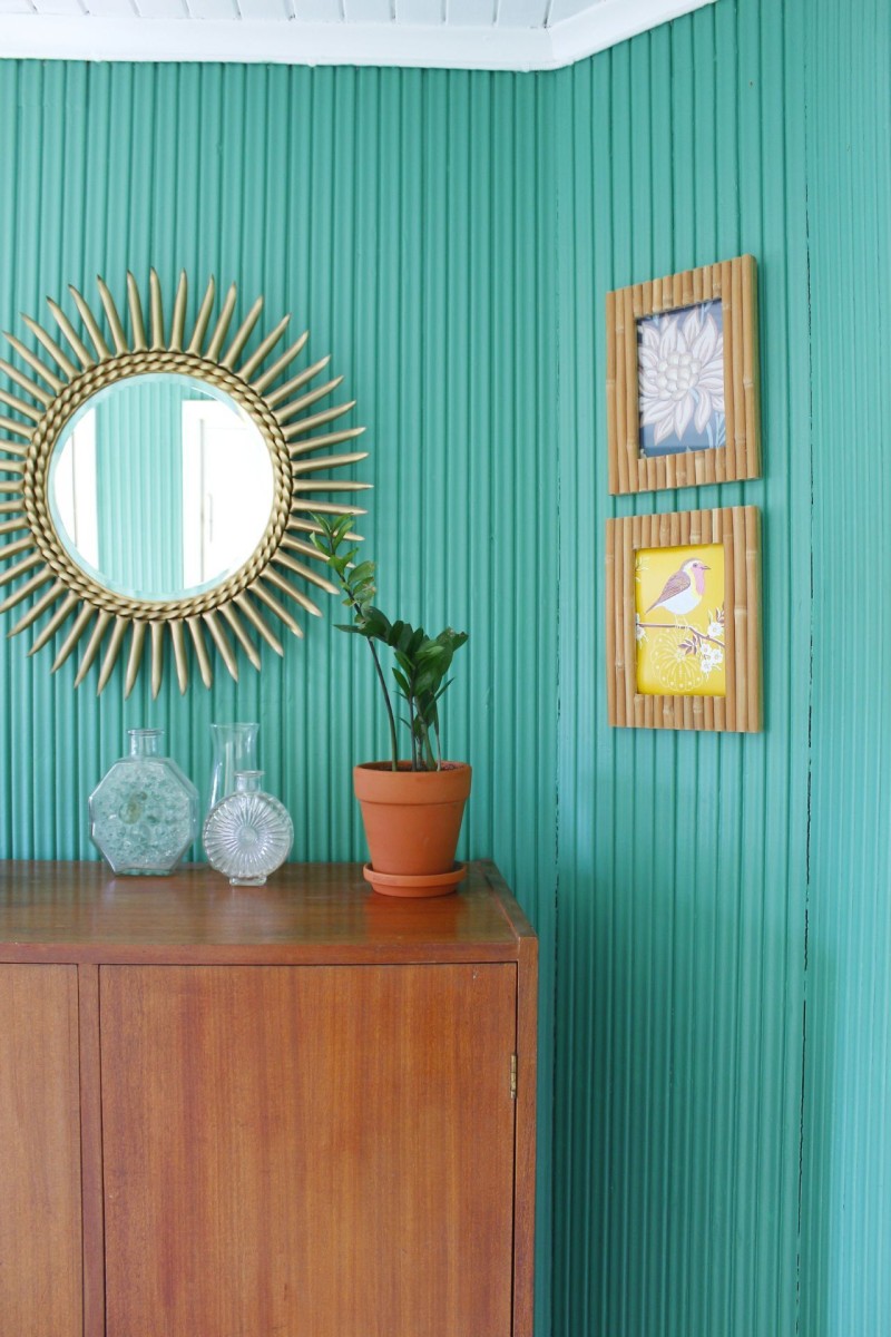 ryškiai žalia koridoriaus siena, dekoruota mediniais baldais
